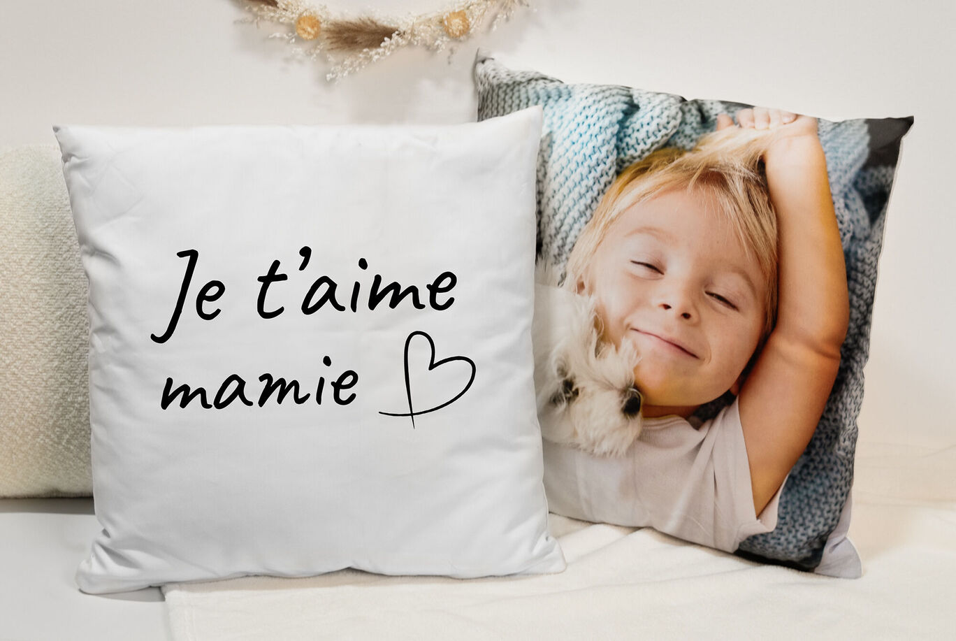 Un coussin avec le texte 'Je t'aime mamie' et un autre coussin avec un enfant dessus.