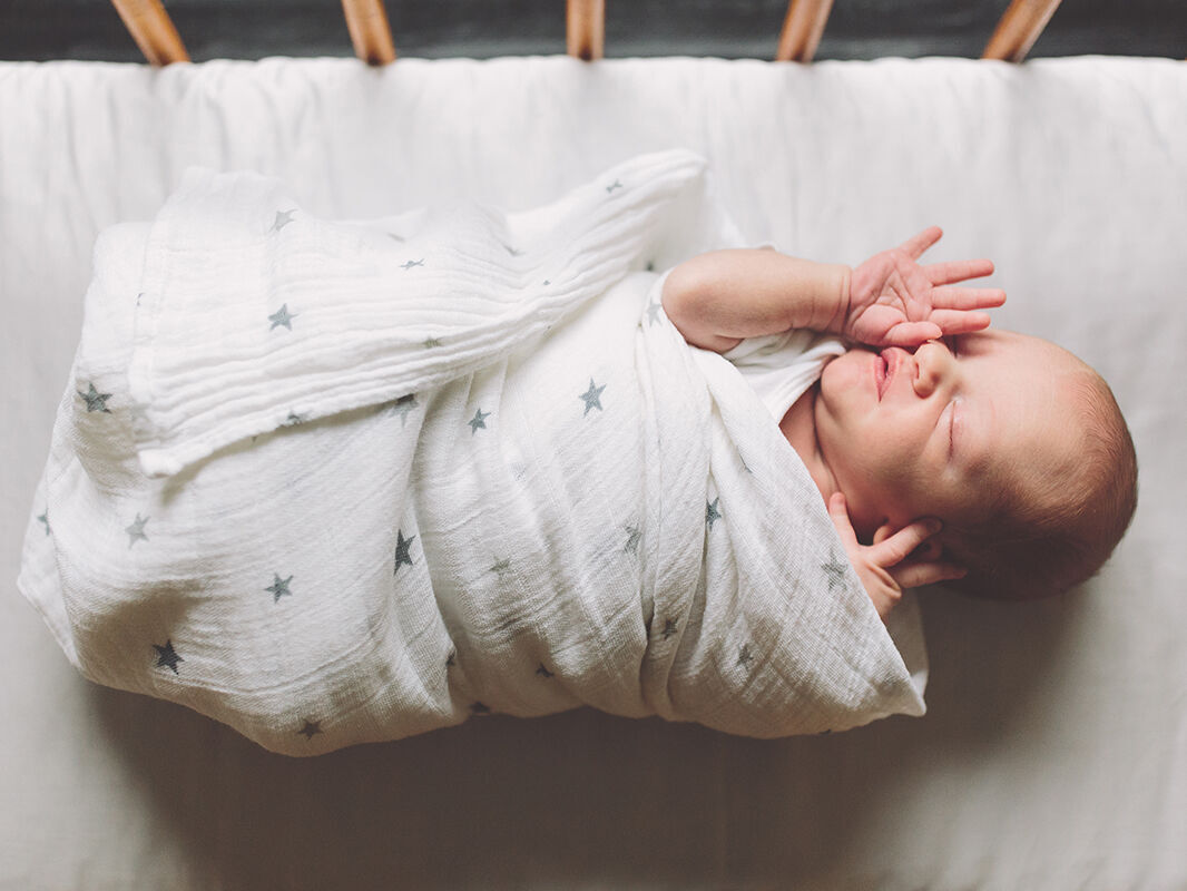 Un bébé adorable enveloppé avec un motif d'étoiles sur une couverture claire.