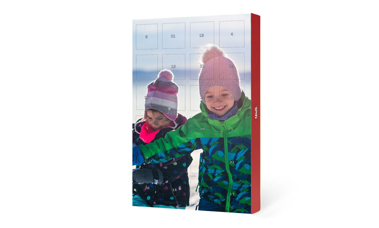 Deux enfants joyeux assis ensemble devant un calendrier de l'Avent dans la neige