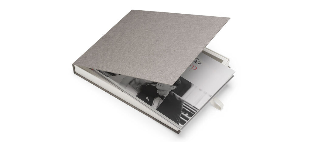 Livre photo CEWE ouvert avec une couverture grise et des images à l'intérieur