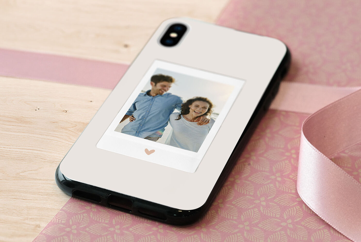Téléphone avec étui photo personnalisé et motif en cœur sur fond en bois.