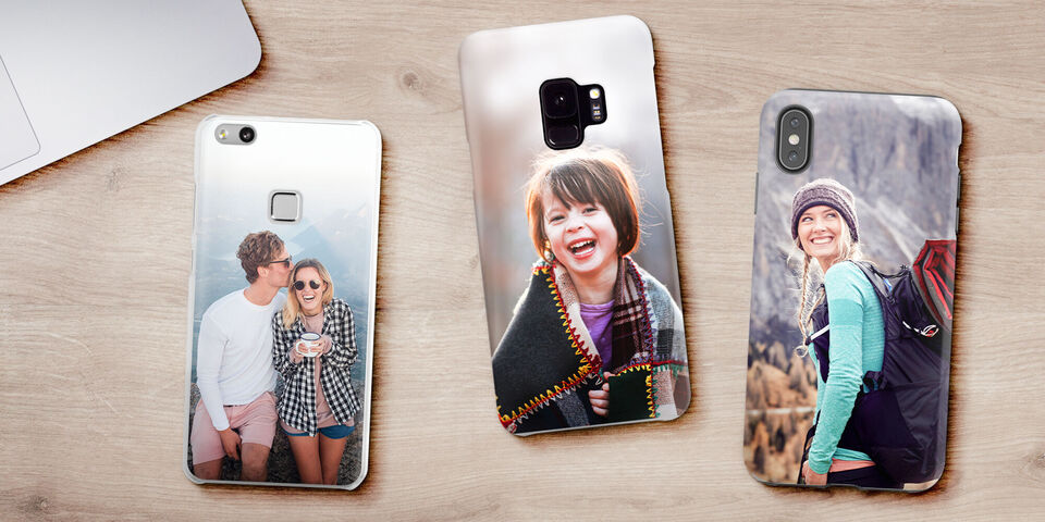 Trois coques de téléphone personnalisées avec photos d'amis et sorties reposant sur une table en bois.