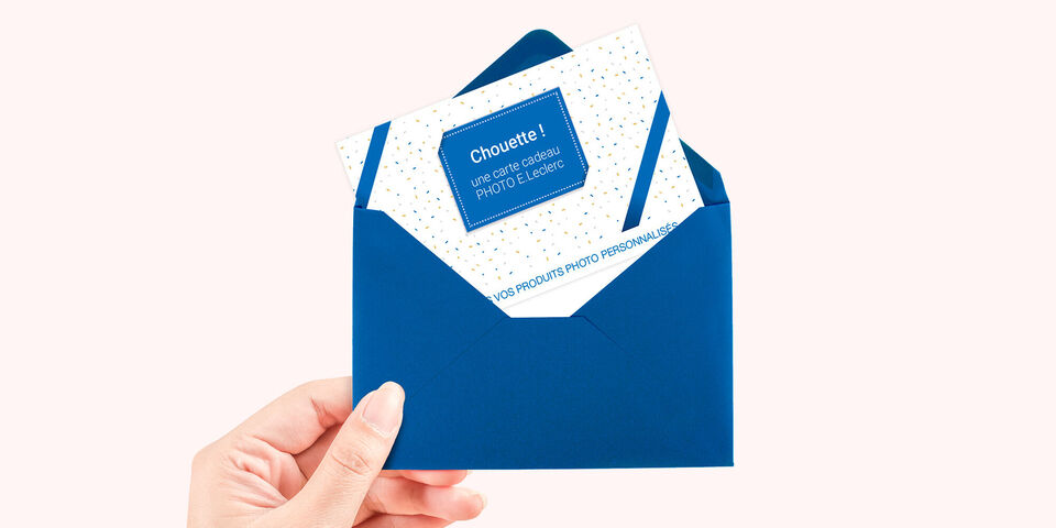 Une main tient une enveloppe bleue avec une carte de vœux spéciale. La carte a un design blanc avec des points colorés et un beau texte.