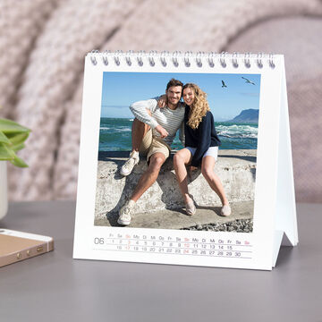 Un couple profite d'une journée ensoleillée à la plage, souriant dans un calendrier CEWE.
