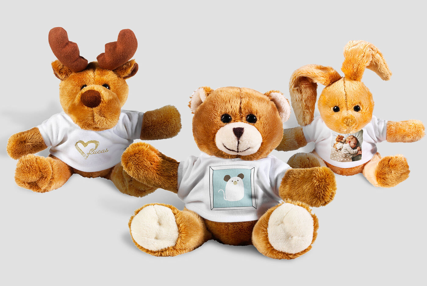 Trois peluches douces : un renne, un ours en peluche et un lapin portant des T-shirts mignons.