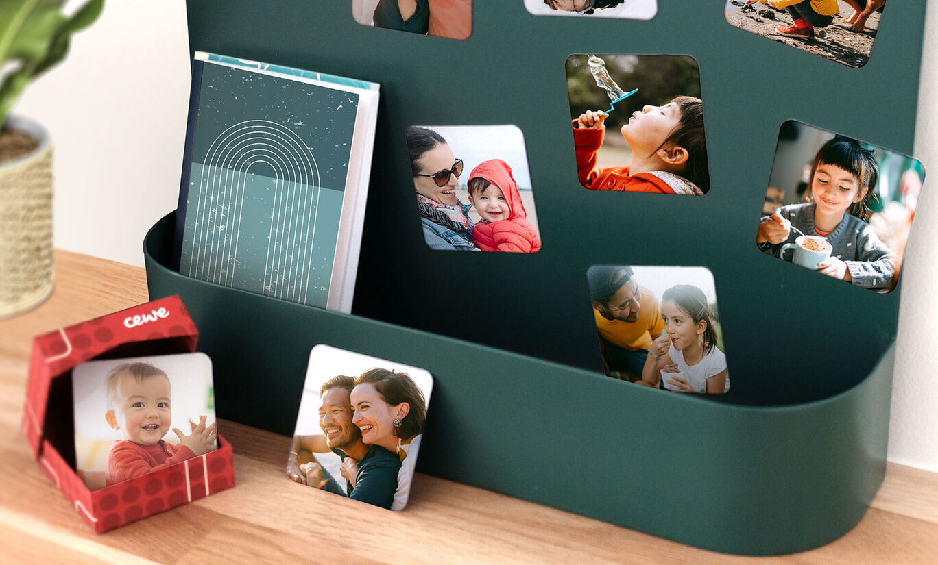 Un mur avec des photos colorées, dont un livre photo CEWE et une petite boîte cadeau.