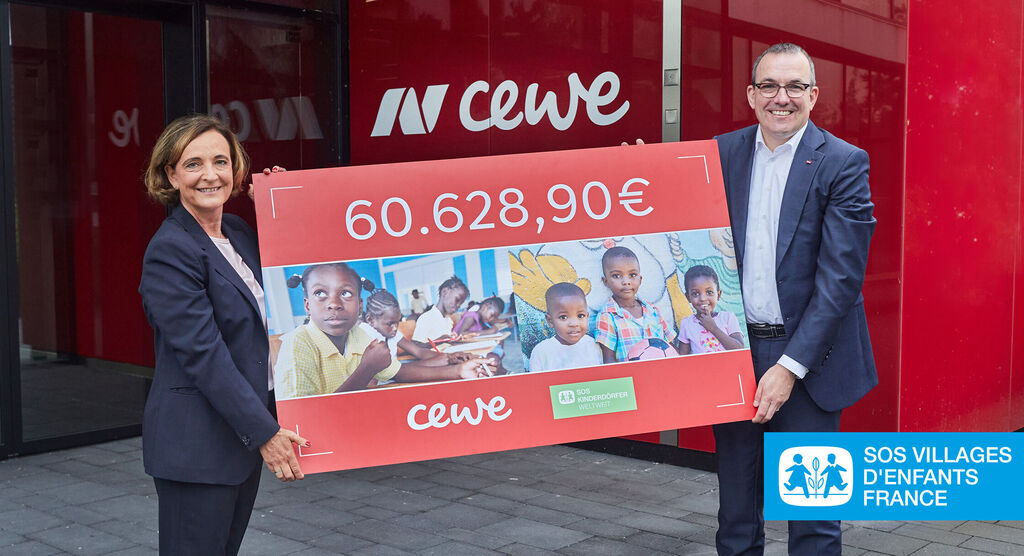 Deux personnes montrent un grand chèque de 60.628,90€ pour SOS Villages d'Enfants.