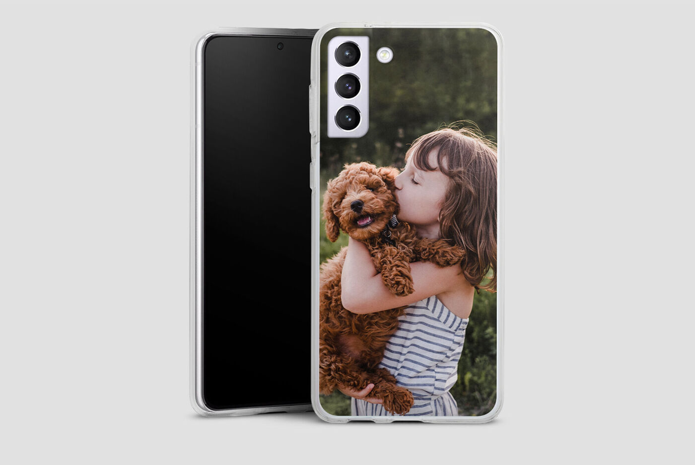Fille tenant un chien heureux dans ses bras, avec un smartphone en arrière-plan.