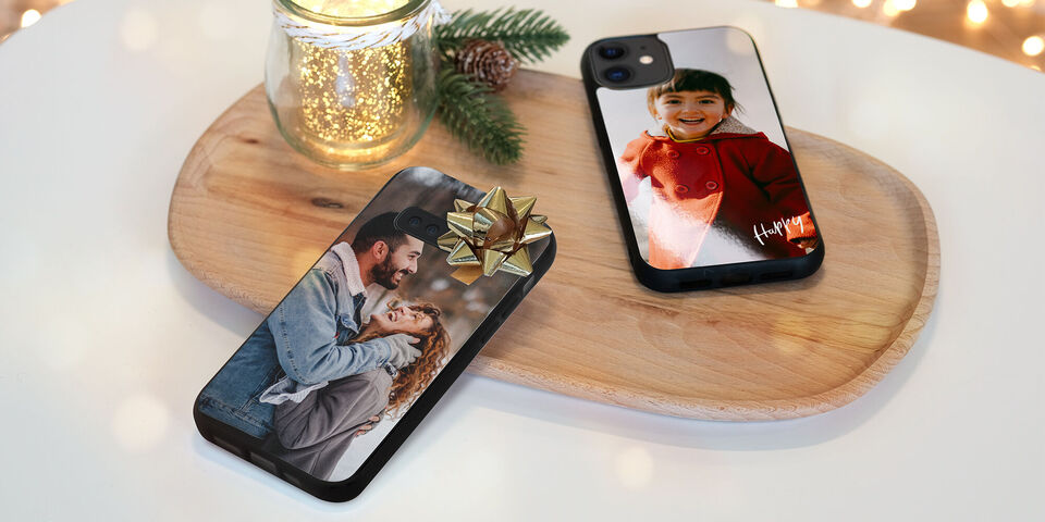 Deux téléphones personnalisés sur une planche en bois avec une déco de Noël, l'un a un joli nœud.