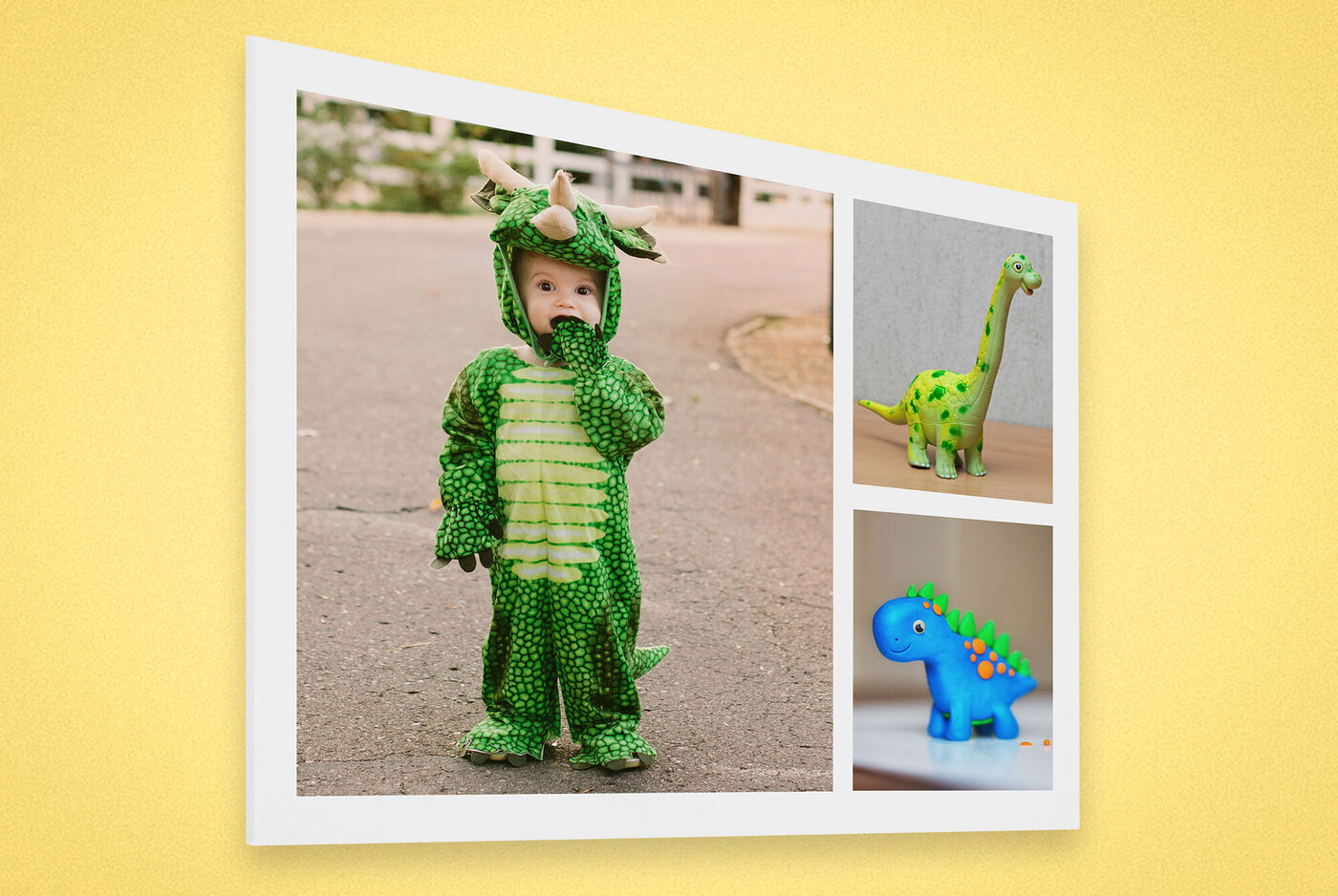 Un petit enfant porte un costume de dinosaure vert et joue dans la rue. Deux dinosaures jouets sont à côté.