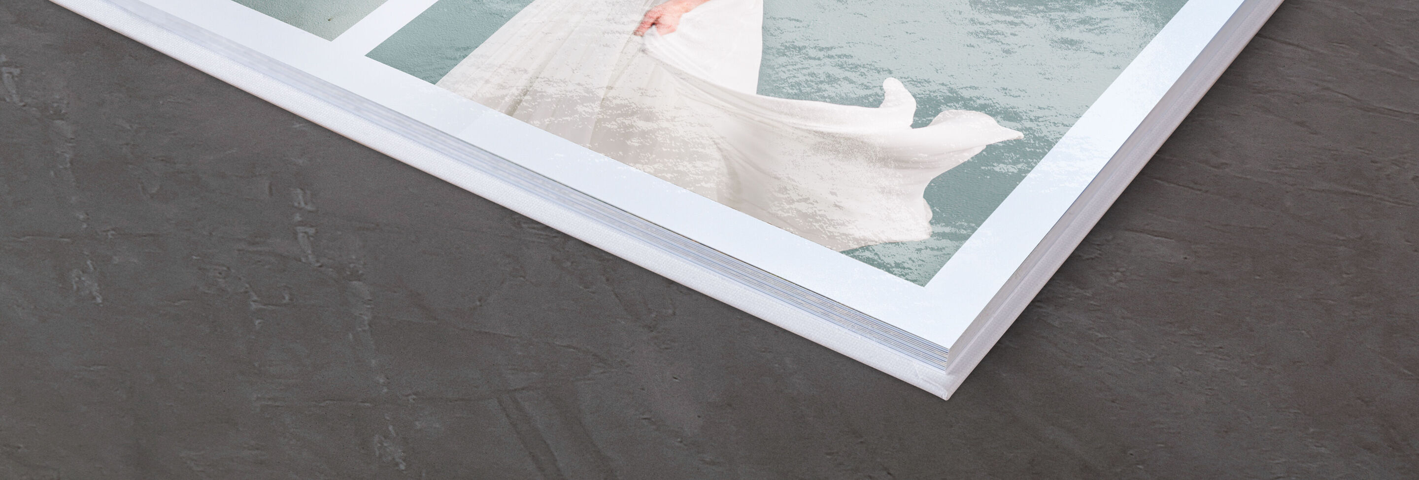 Gros plan d'un livre photo CEWE ouvert avec une couverture claire et une page structurée élégante.