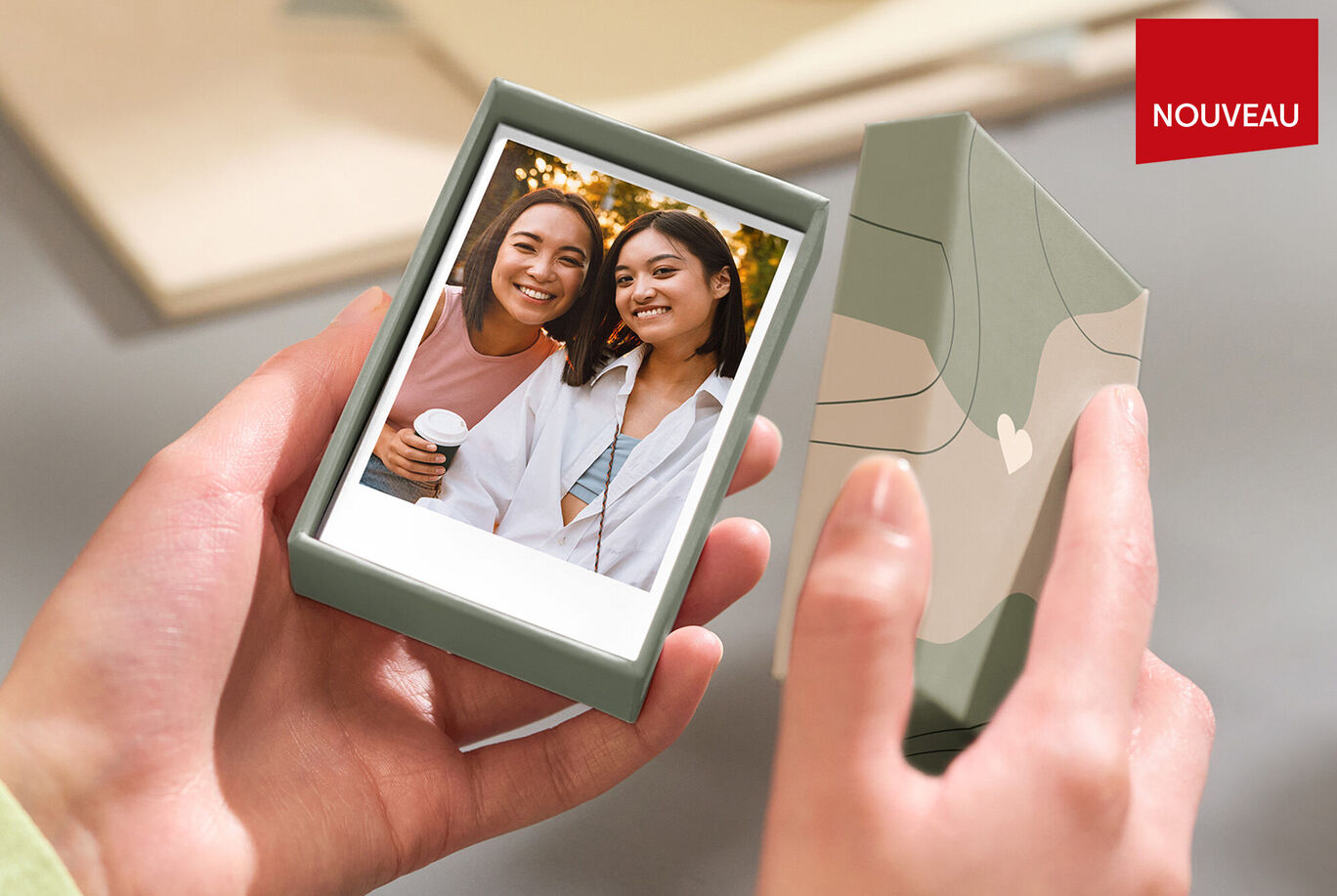 Une personne tient une boîte cadeau soigneusement conçue avec une photo à l'intérieur.