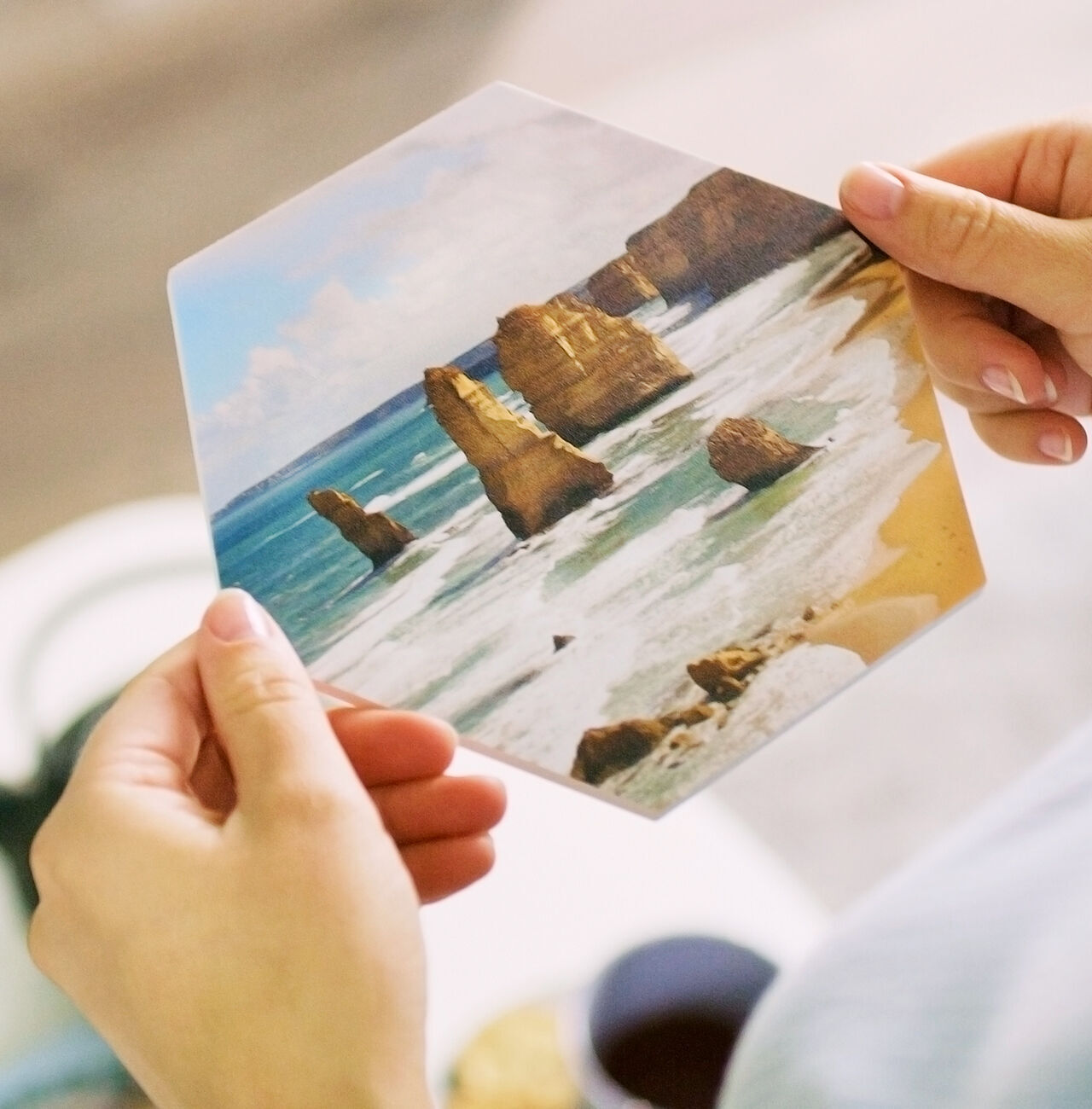 Une personne tient une carte photo hexagonale des célèbres Twelve Apostles sur la côte australienne.