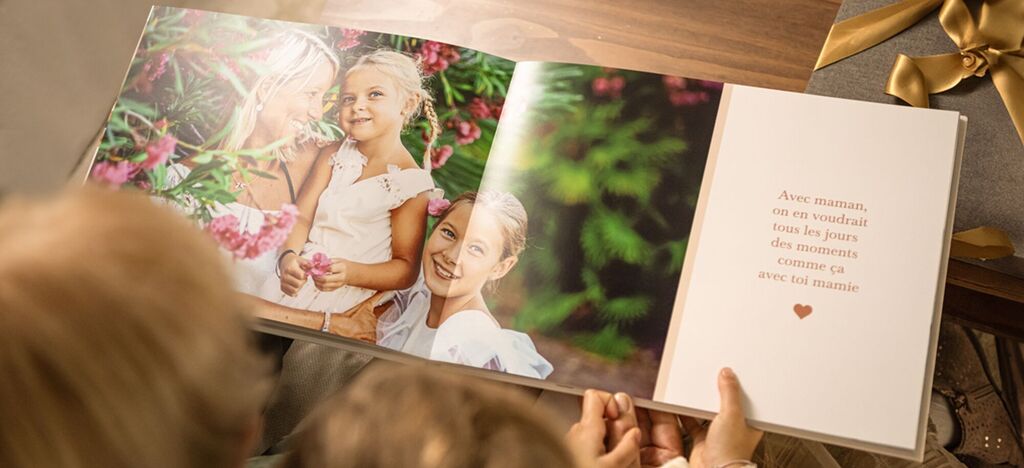 Un livre photo ouvert avec deux enfants dans une prairie fleurie, tenant des fleurs et souriant.