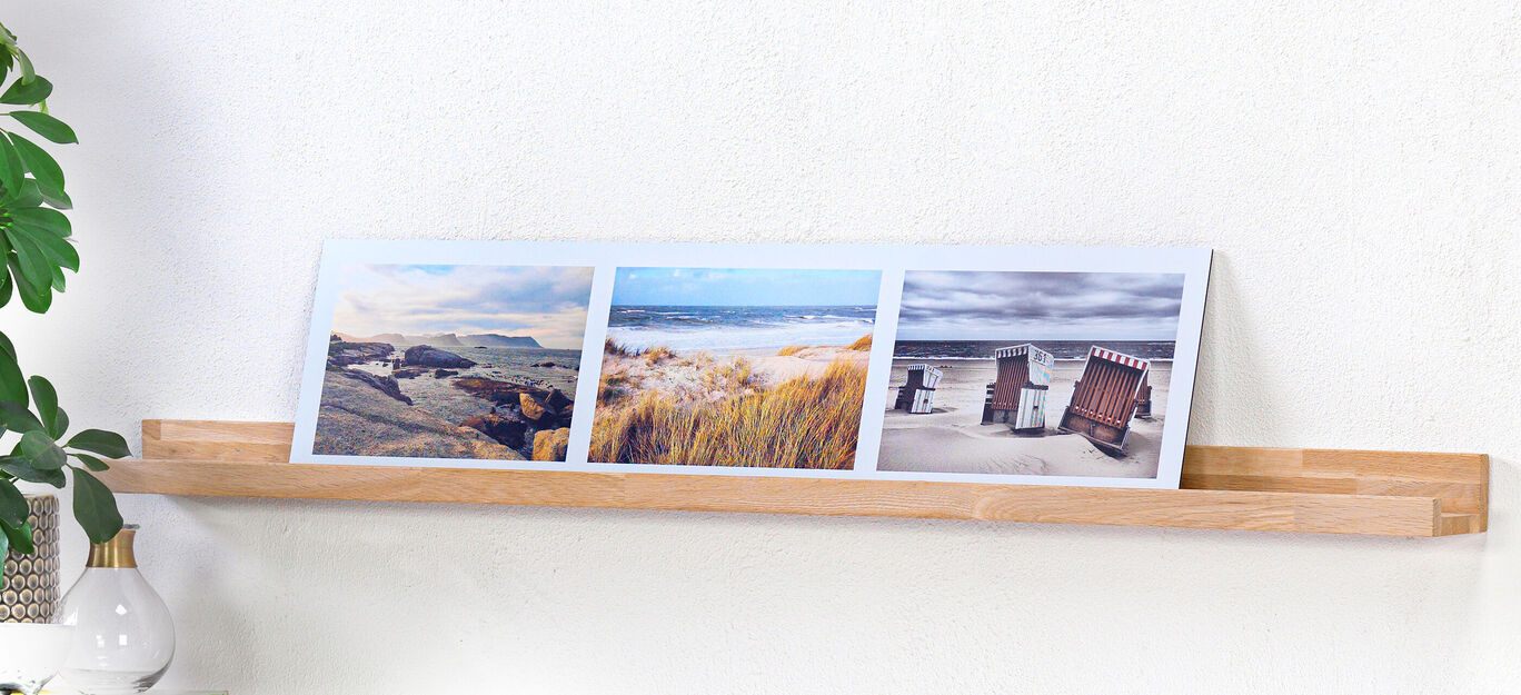 Trois photos sur une étagère en bois avec des motifs de plage et un bâtiment historique sous un ciel sombre.