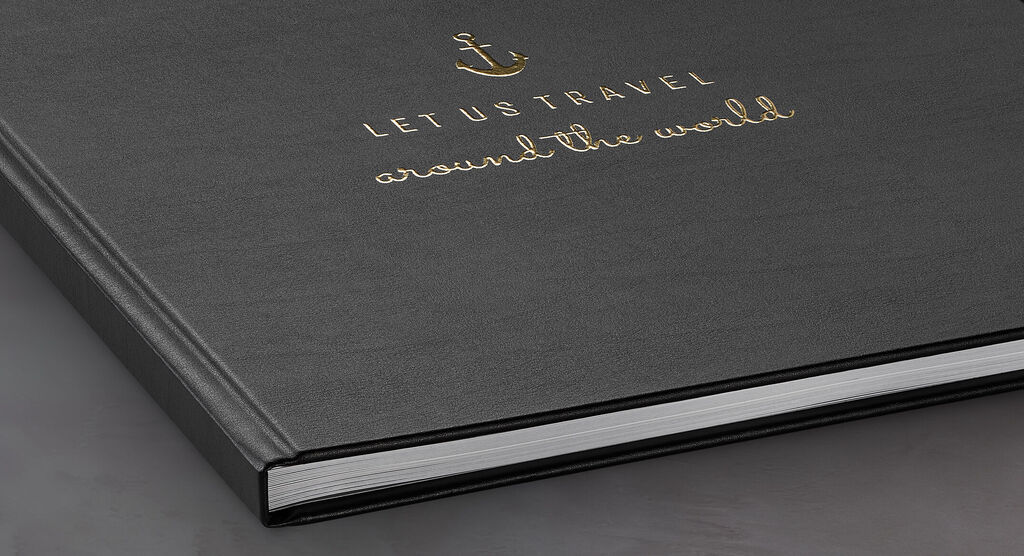 Livre photo noir avec inscription dorée "LET US TRAVEL autour du monde"