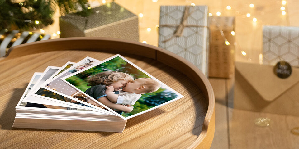 Quatre photos d'enfants heureux sur une table, entourées de cadeaux et de lumières