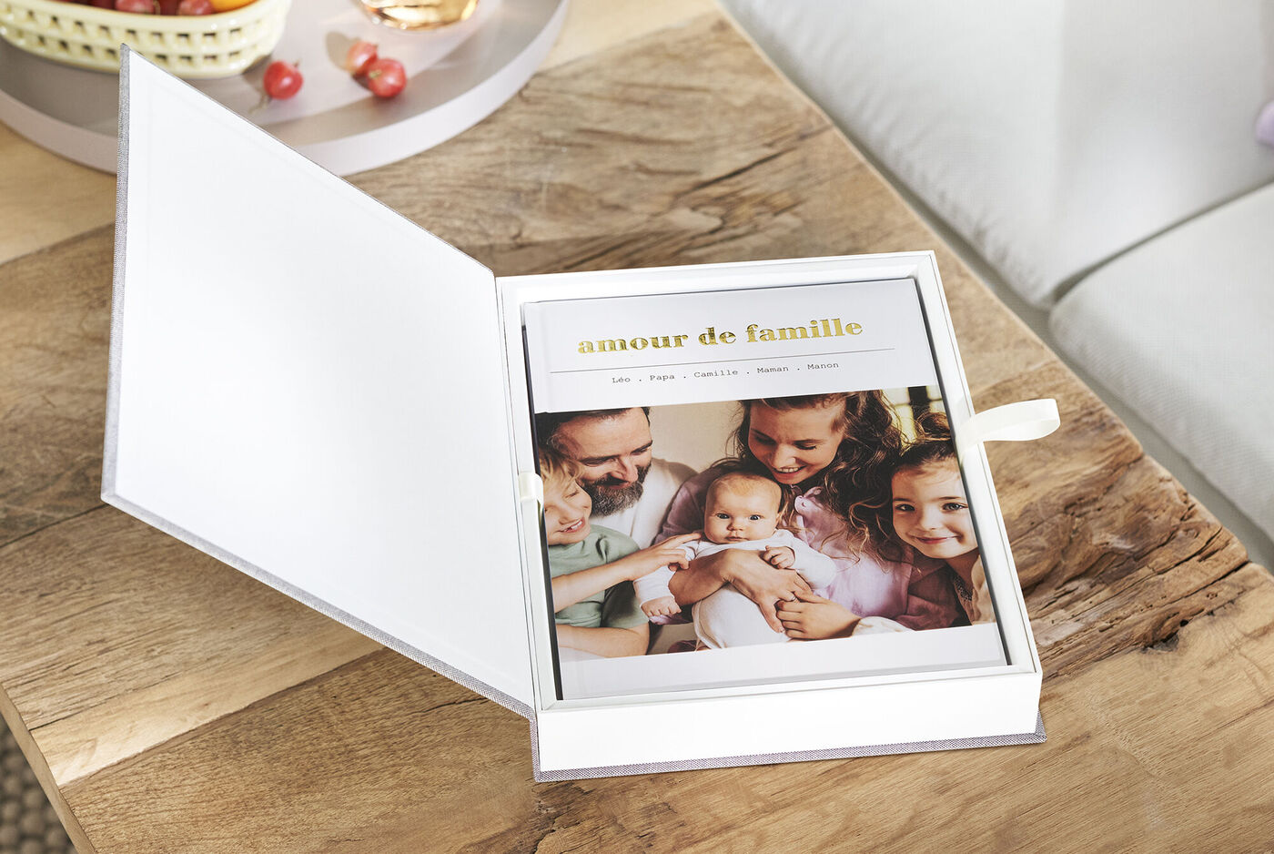 Un CEWE Fotobuch ouvert avec le titre 'amour de famille', montrant des moments familiaux sur une table en bois.