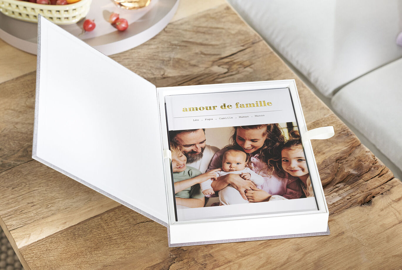 Un CEWE Fotobuch ouvert avec le titre 'amour de famille', montrant des moments familiaux sur une table en bois.