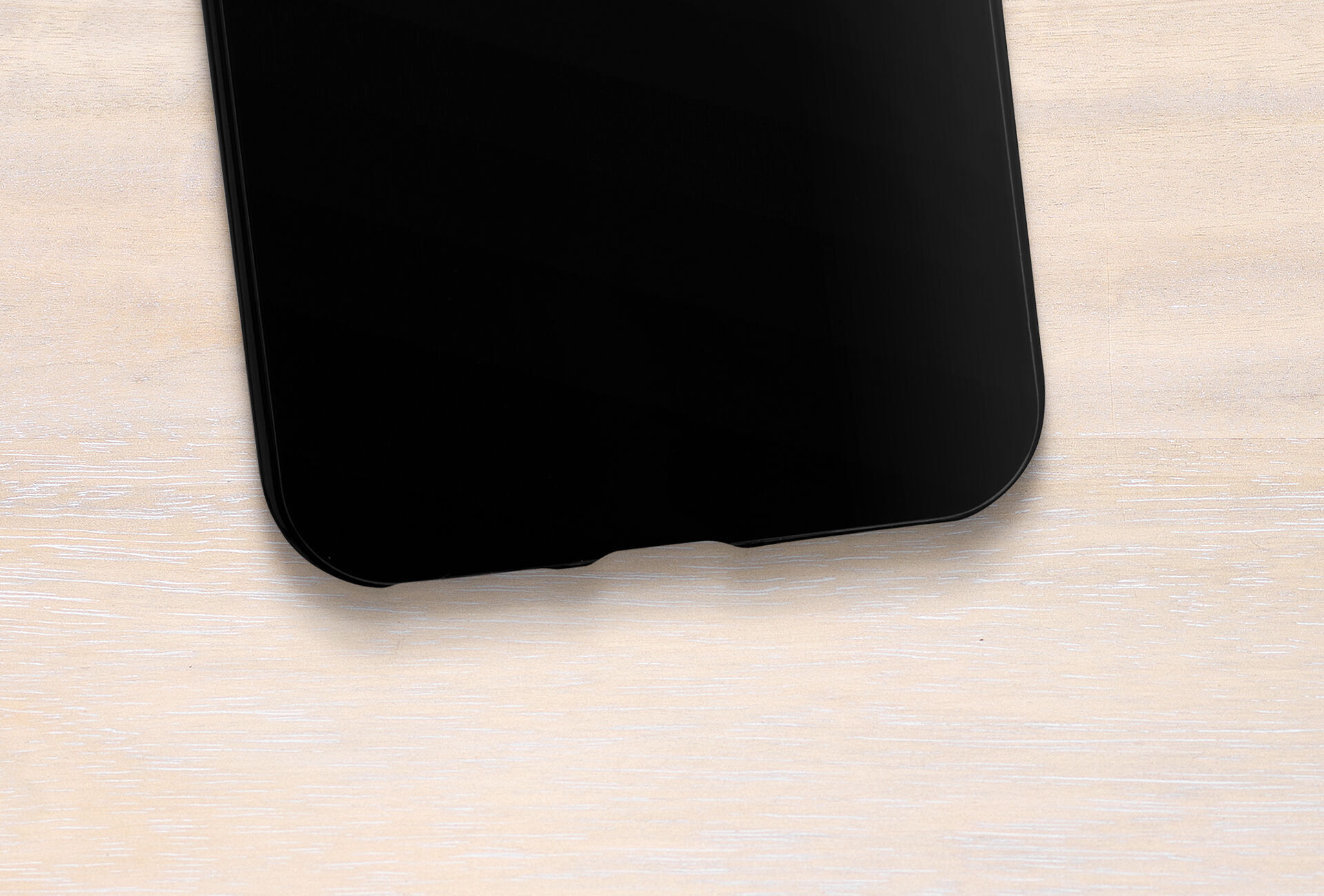 Smartphone noir sur une table en bois clair.