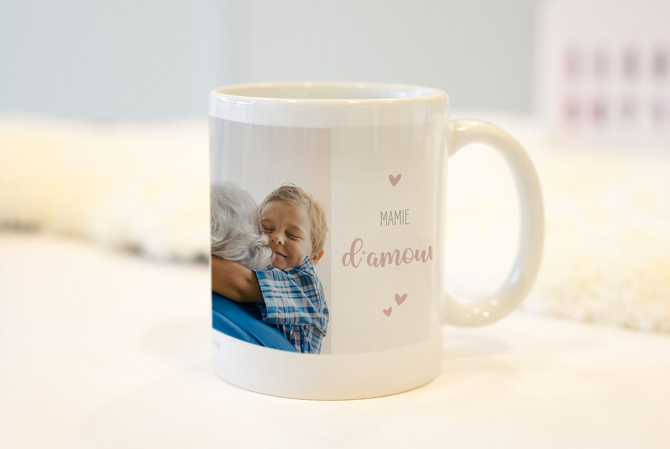 Tasse avec un design chaleureux et le texte 'Mamie d'amour', entourée de cœurs.