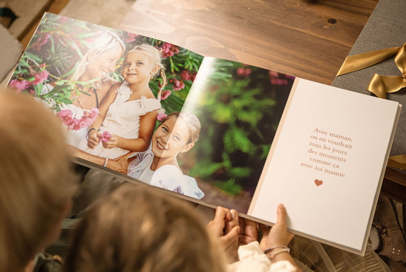 Deux personnes regardent un CEWE ALBUM PHOTO avec des fleurs colorées derrière elles.
