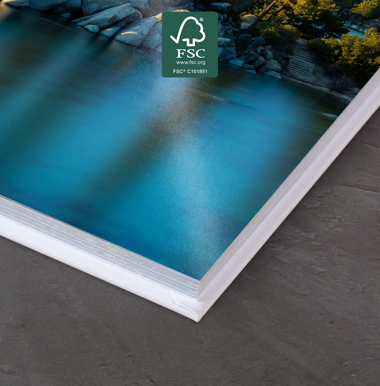 Gros plan d'un livre photo CEWE ouvert, menant à un lac bleu et des arbres