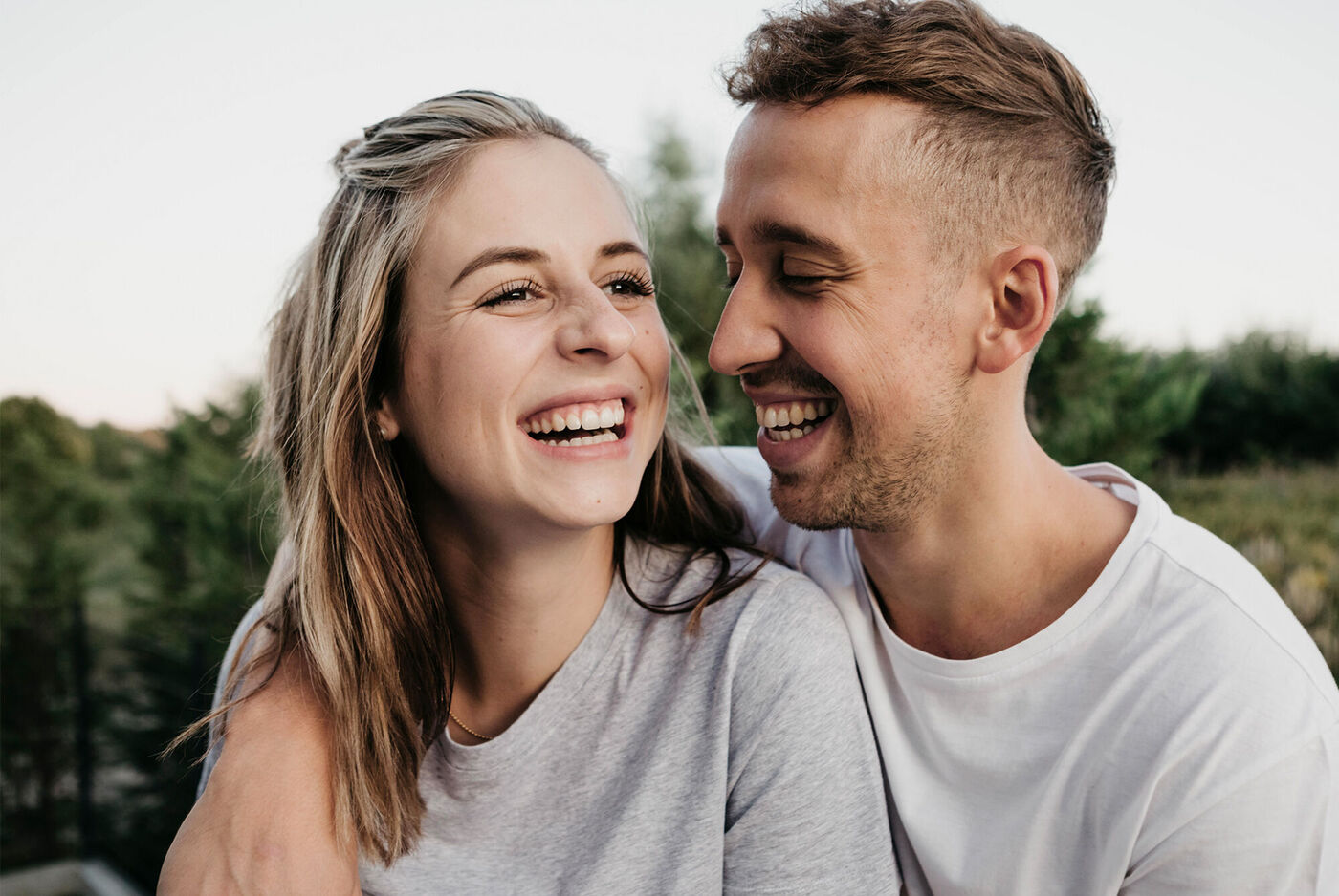 Un couple profite d'un moment ensoleillé à l'extérieur, souriant et uni.