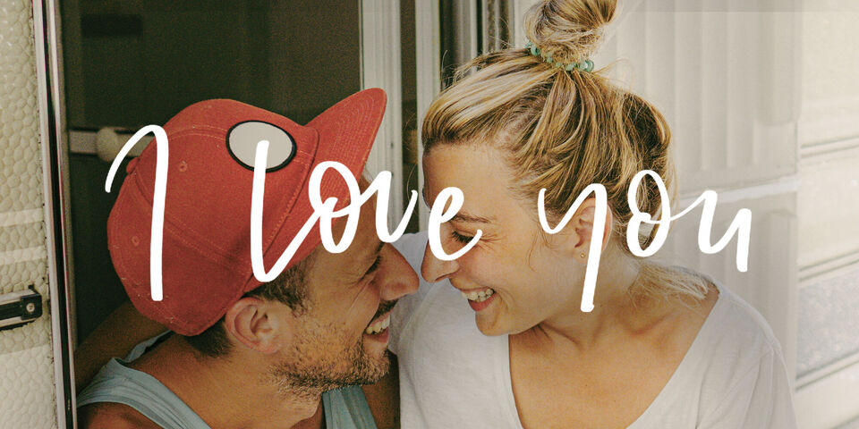 Un couple profite d'un moment de complicité dans un camping-car avec un message d'amour en arrière-plan.