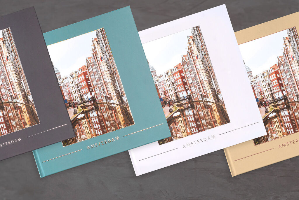 Trois couleurs de livres photo CEWE avec le titre 'Amsterdam', disposés élégamment.