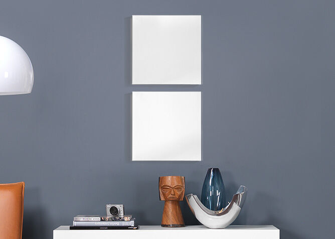Deux cadres vides blancs sur un mur gris au-dessus d'une table avec des objets décoratifs.
