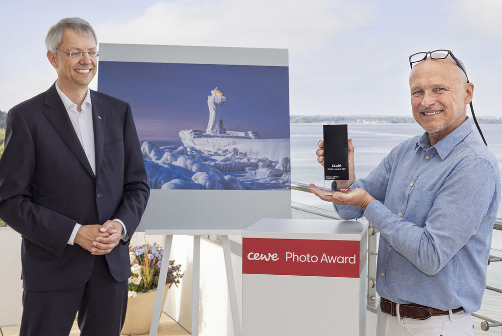 Deux personnes lors de la remise des prix CEWE Photo Award, une photo impressionnante en arrière-plan.