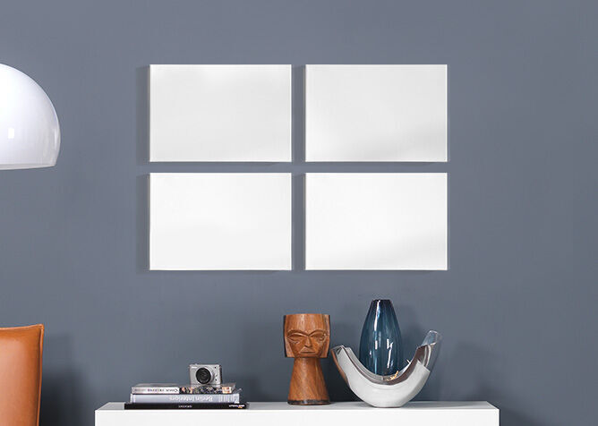 Cadres blancs vides sur un mur gris, décorés de vases élégants et d'une caméra.