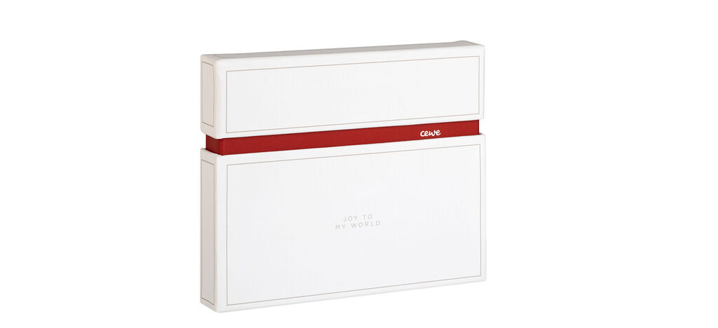 Un élégant CEWE PHOTOBOOK en blanc avec un ruban rouge.