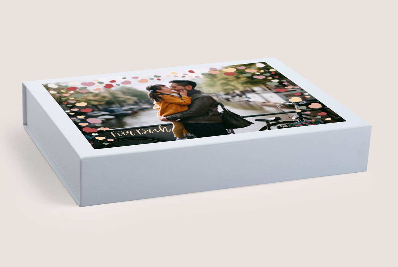 Boîte CEWE FOTOBUCH avec une photo d'un couple s'enlaçant lors d'une promenade romantique.