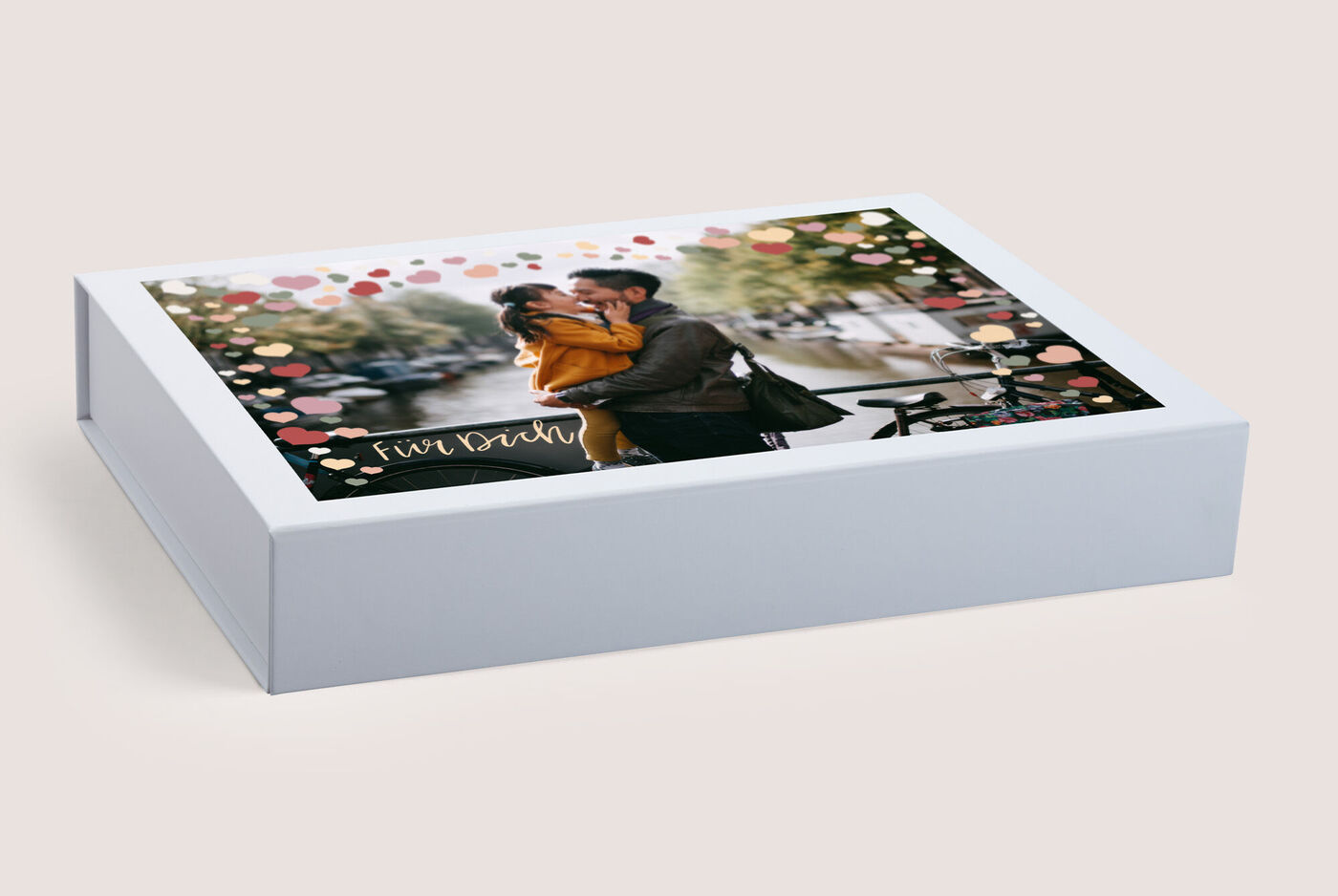 Boîte CEWE FOTOBUCH avec une photo d'un couple s'enlaçant lors d'une promenade romantique.