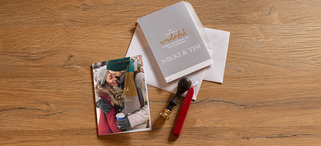 Un livre photo CEWE et des cartes sur une table en bois. Le livre montre une femme âgée avec un proche.