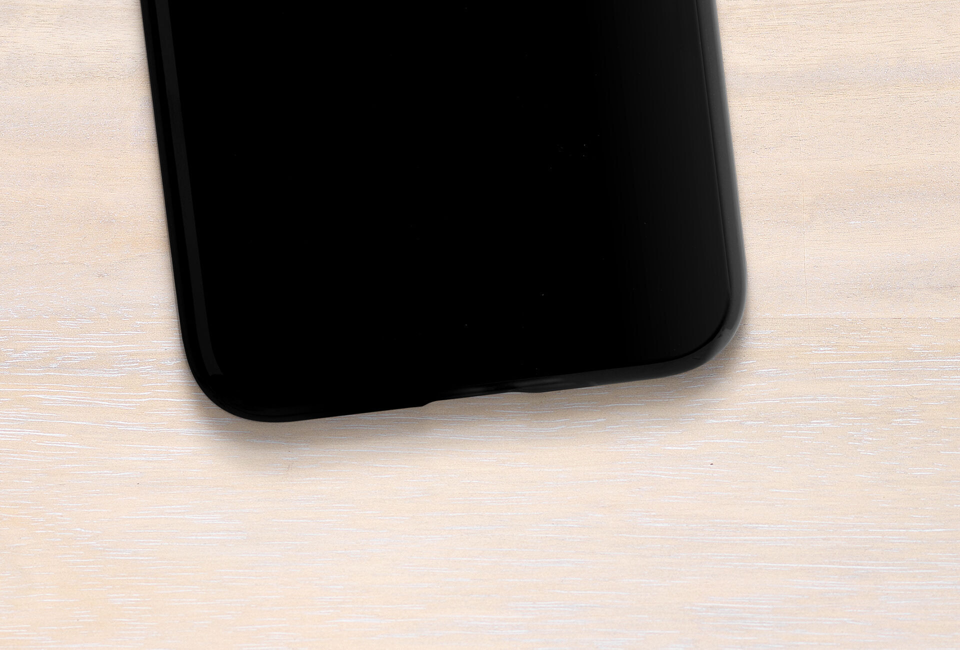 Smartphone noir sur une table en bois clair.