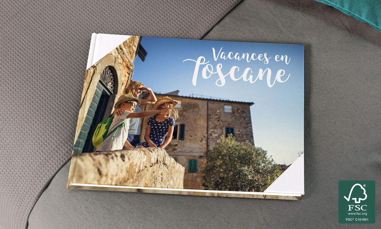 Deux enfants jouant avec des chapeaux de paille sur un balcon en Toscane, entourés d'anciens bâtiments.