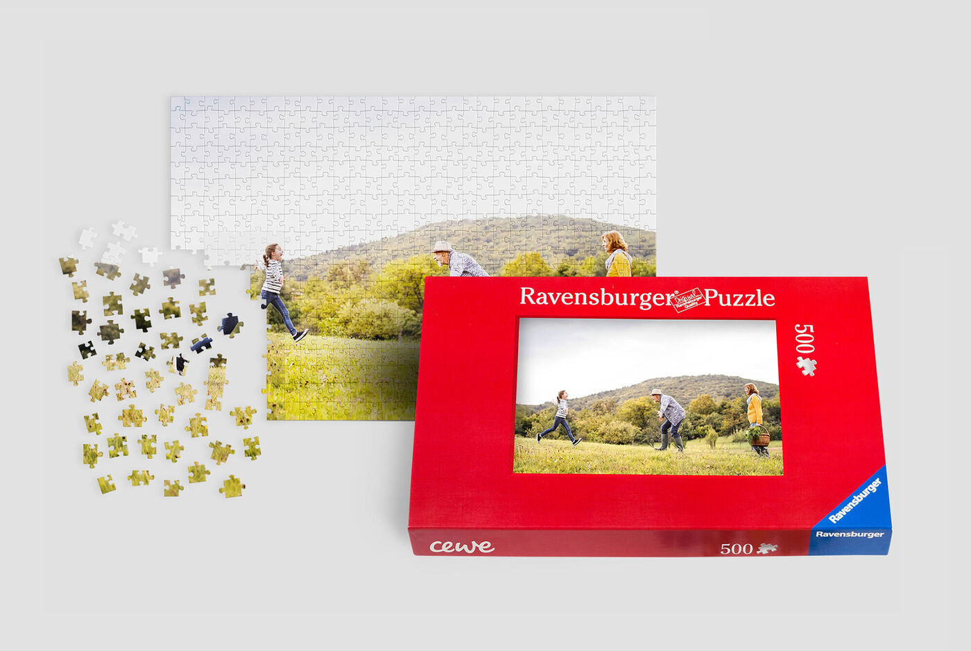 Un groupe de personnes pique-nique en plein air, travaillant sur un puzzle Ravensburger. Les pièces sont éparpillées dans l'herbe.