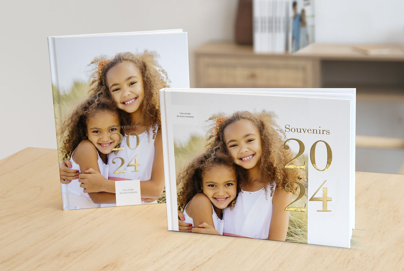 Deux beaux livres photos CEWE avec des souvenirs de 2024 sur une table en bois.