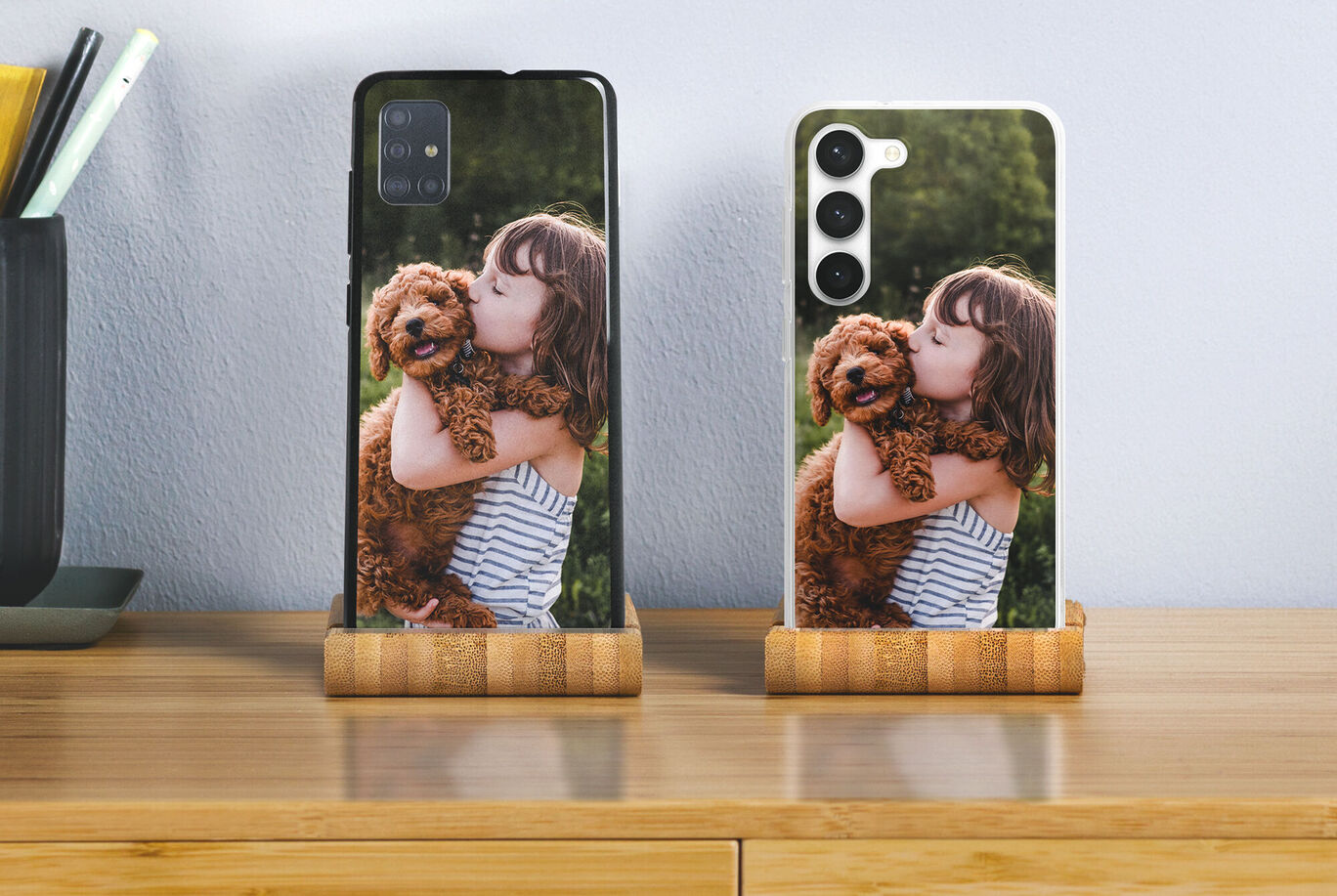 Deux téléphones avec des coques personnalisées montrant une fille étreignant tendrement un chien.