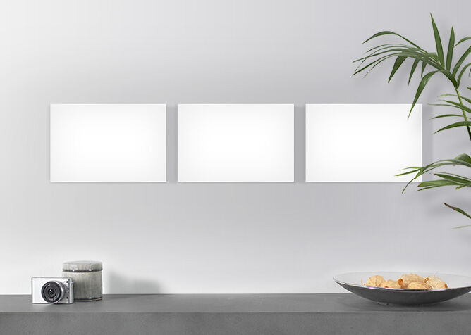 Trois cadres photo vides sur un mur au-dessus d'une table avec un bol de collations et une caméra.