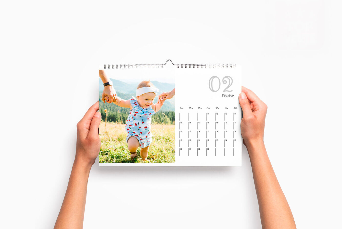 Des mains tiennent un enfant se tenant dans un champ. C'est une page de calendrier pour février avec beaucoup de cases.