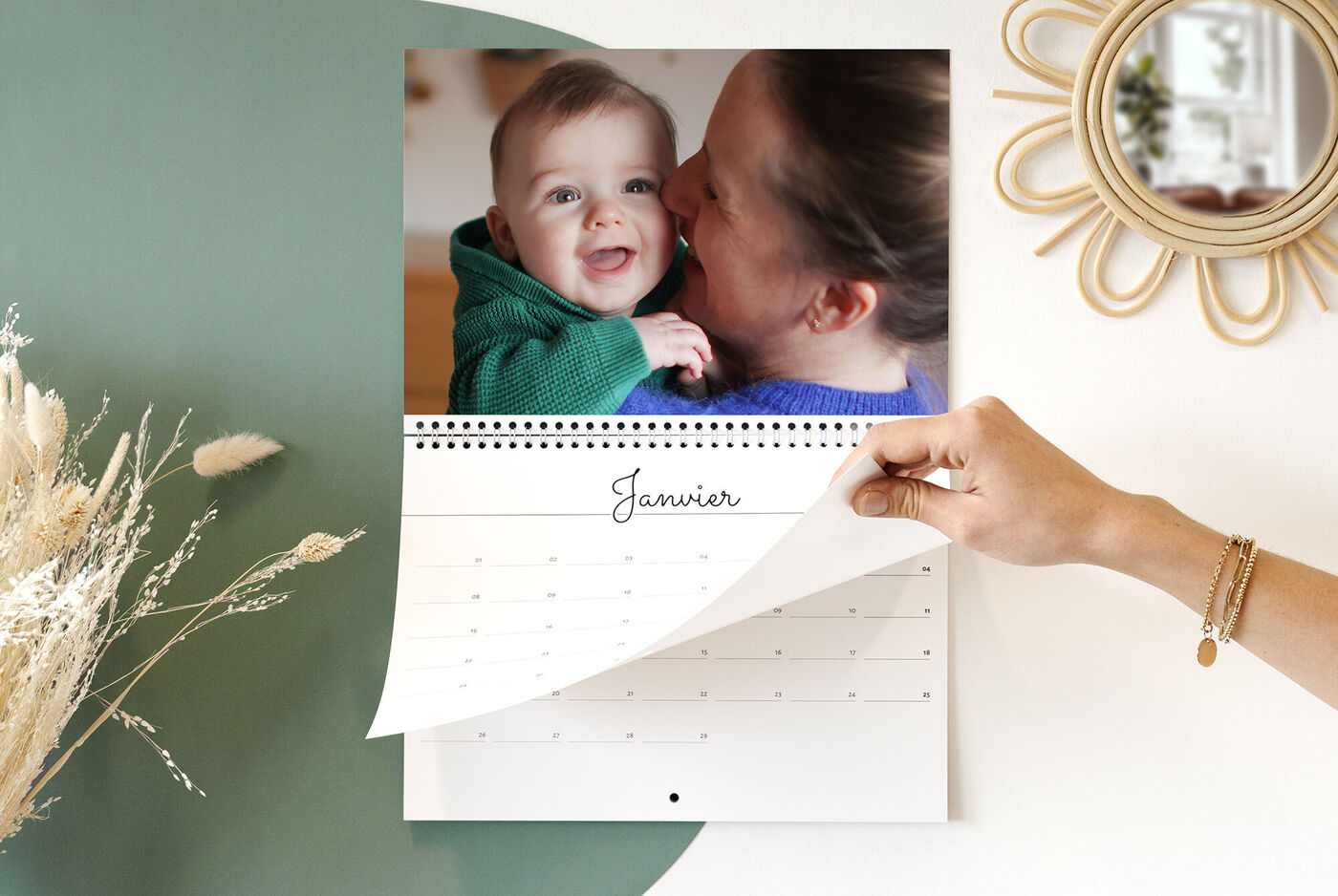 Une personne feuillette un calendrier photo pour le mois de janvier, tandis qu'une autre personne est visible.