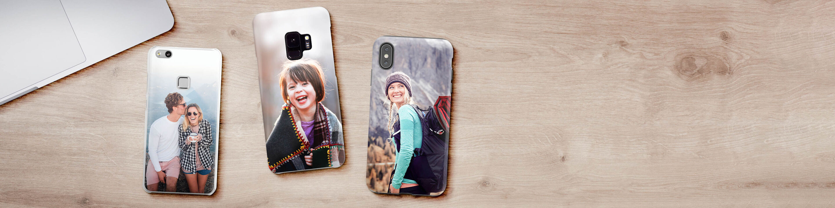 Trois coques de téléphone créatives avec photos personnelles sur un bureau en bois.
