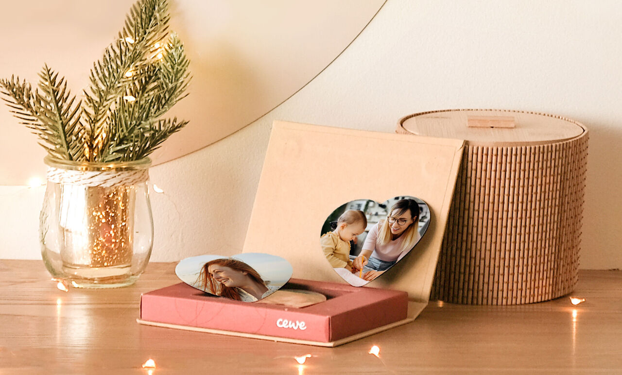 Un CEWE photo livre soigneusement conçu avec deux photos en forme de cœur sur une table avec un bel élément décoratif.