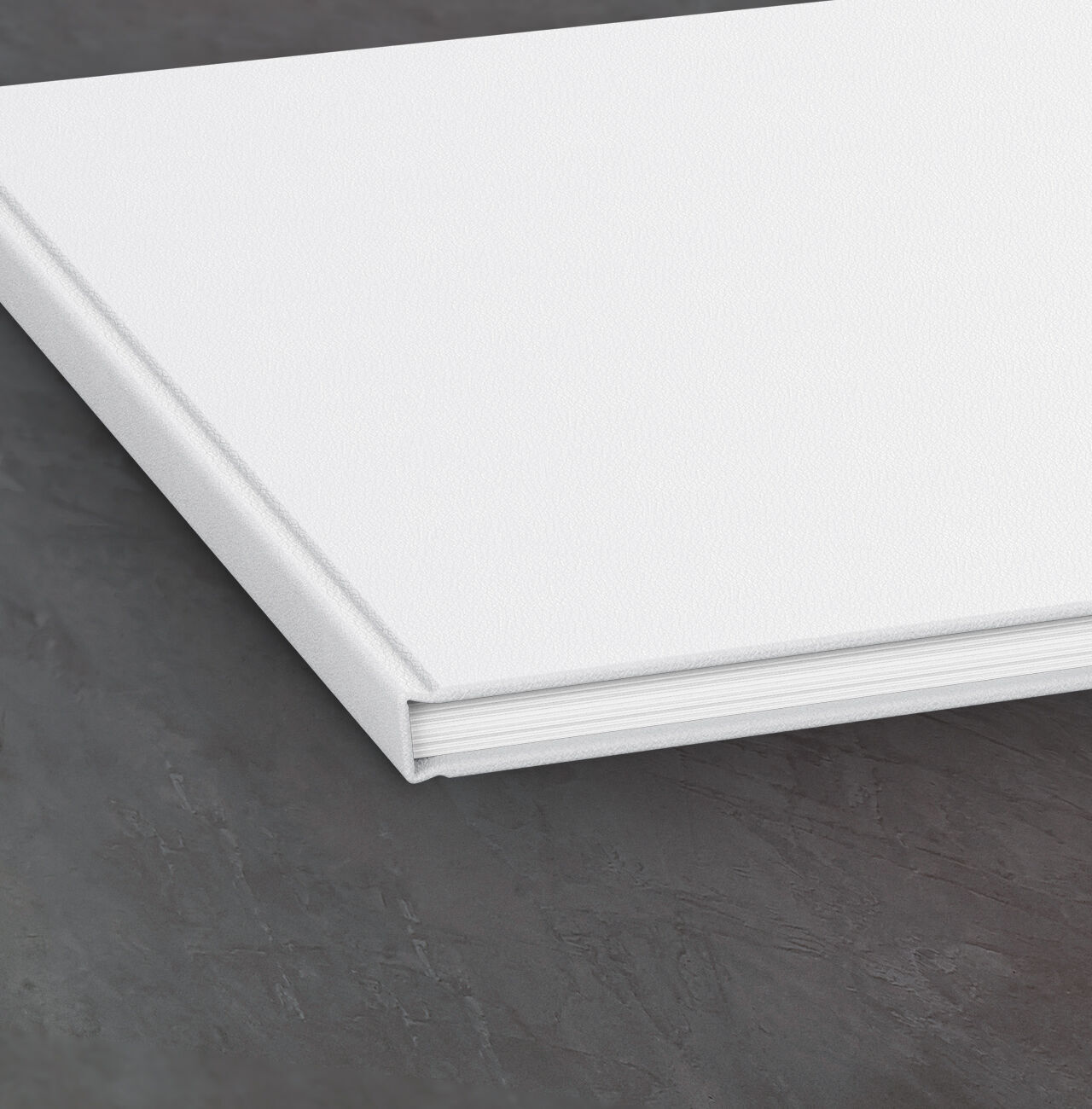 Un livre photo CEWE blanc fermé sur une surface sombre.