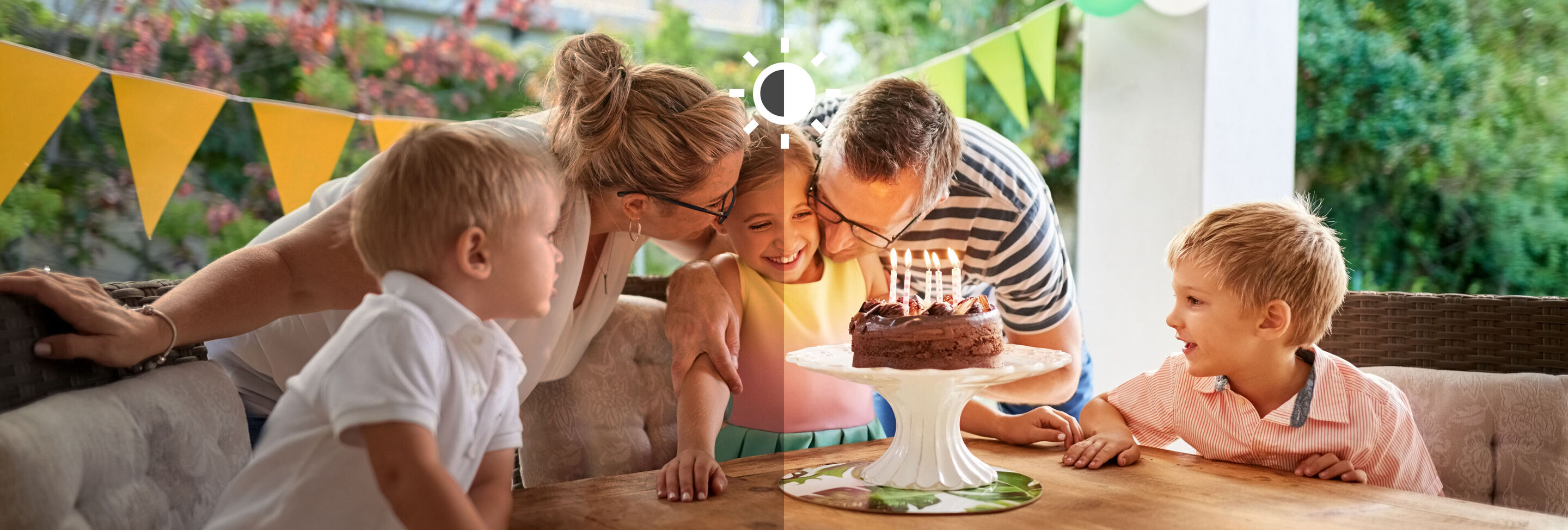 Une famille célèbre un anniversaire avec un gâteau et des bougies dans le jardin.