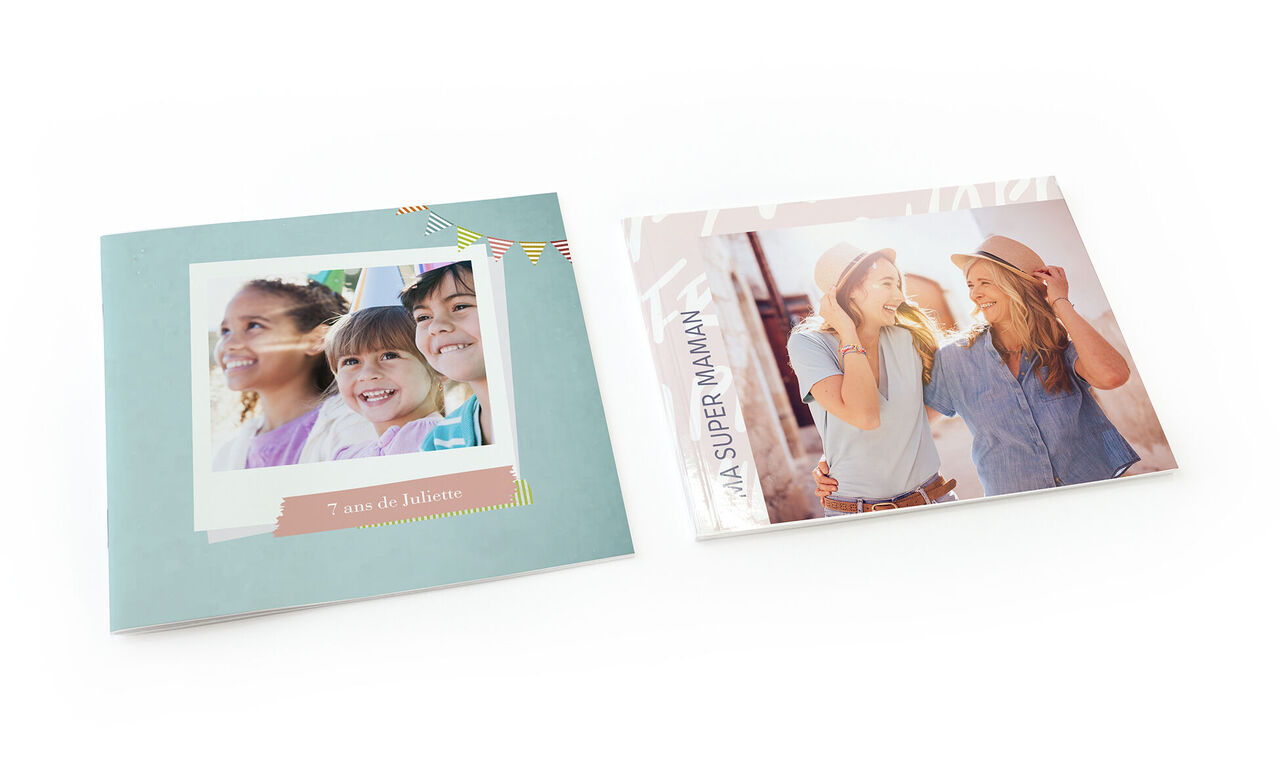 Deux femmes souriantes portant des chapeaux, avec un livre photo à leurs côtés.